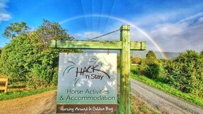 A sign for 'HACK 'n Stay' offering horse activities and accommodation in Golden Bay.