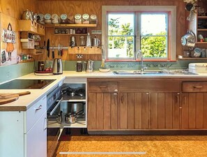 A kitchen with wooden cabinets, a sink, and various kitchen utensils.