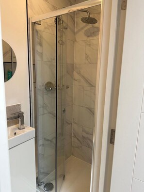 A glass-enclosed shower with a handheld showerhead and a wall-mounted faucet. - Studio Sleeps 2 Near Elephant & Castle (London)