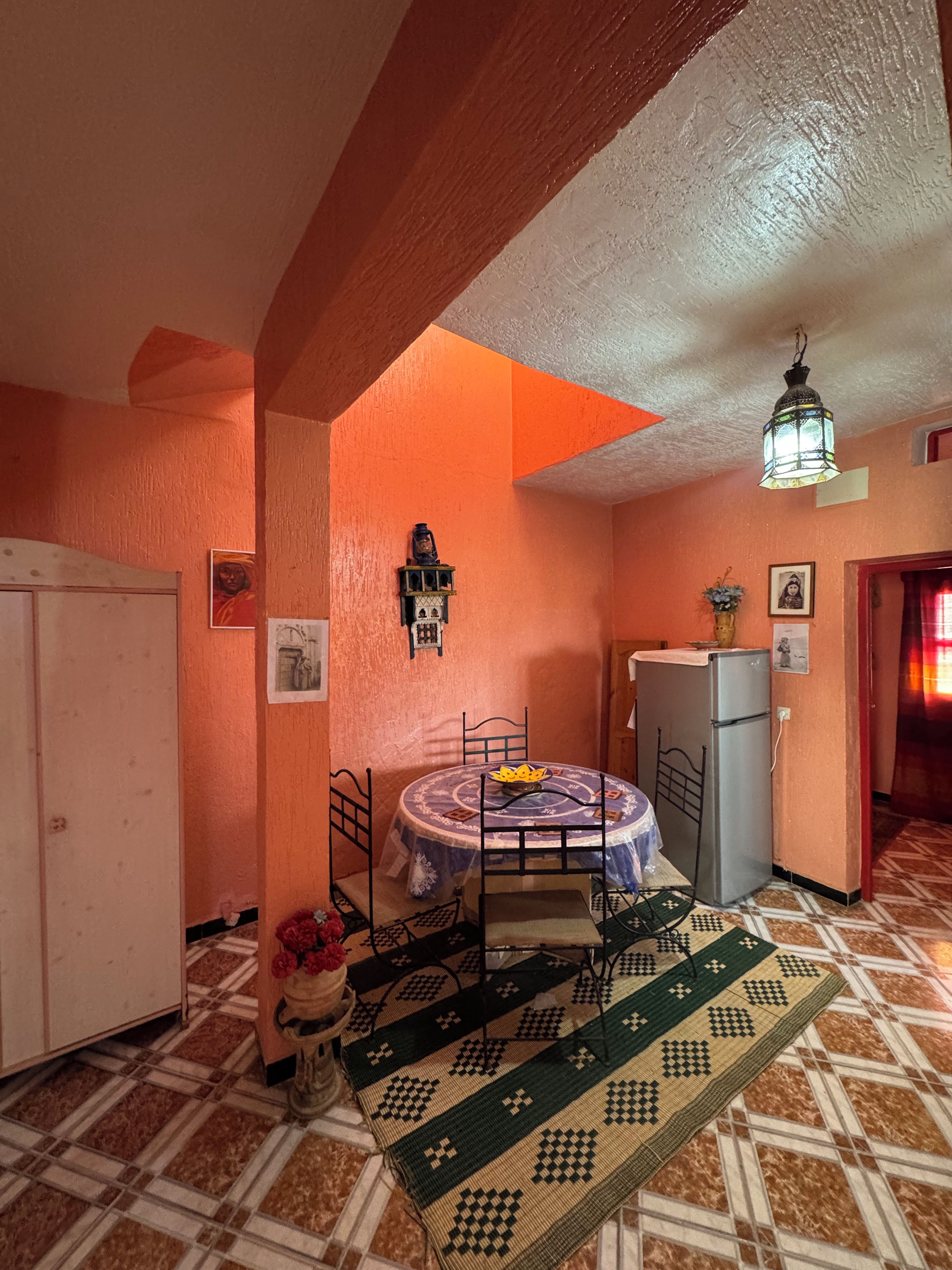 Une cuisine de taille réduite comprenant un coin repas, un réfrigérateur et un tapis à motifs.