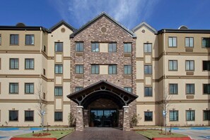 A multi-story building with a central entrance featuring a stone facade and a triangular pediment.
