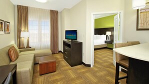 Ein Hotelzimmer mit einer Couch, einem Fernseher, einem Schreibtisch und einem Essbereich.