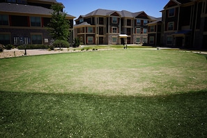 A residential building with multiple floors, large windows, and a well-maintained lawn in front.