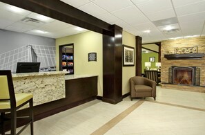 Um hall de hotel com uma mesa de recepção, lareira e área de estar.