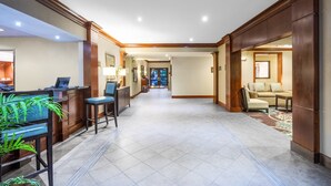 Eine geräumige Lobby mit einer Rezeption, einer Sitzecke und Blick in einen Raum.