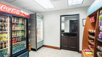 A Coca-Cola refrigerator, a freezer, and a candy shelf in a store.