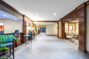 A spacious lobby with a reception desk, seating area, and a view into a room.