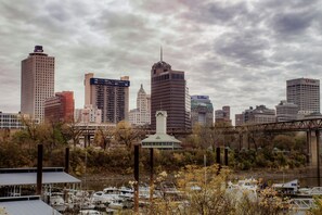 A city skyline with tall buildings, a bridge, and a river with boats.