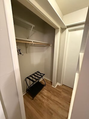 A walk-in closet with a wooden floor, a black metal rack, and a white door. - 2-bedroom/ 2 bath condo near airport and downtown (Austin)