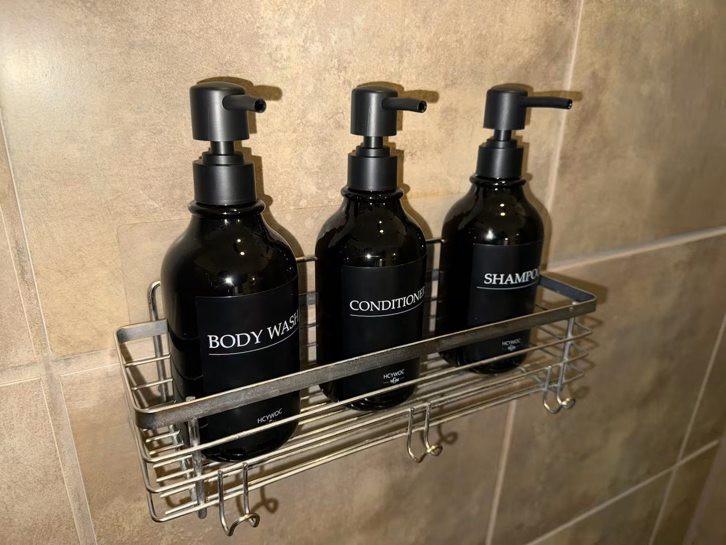 Estante de baño con tres botellas de jabón corporal, acondicionador y champú.