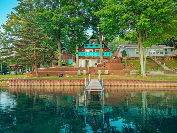 A lakeside property with a dock leading to a house, surrounded by trees and a small dock area.