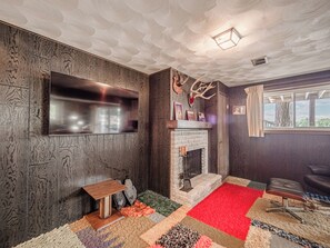 Ein Zimmer mit Kamin, einem an der Wand befestigten Fernseher und einer Hirschdekoration.