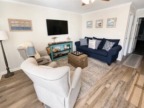A living room with a sofa, armchair, and a television on the wall. - Downtown Ocean City Condo with 2 Full Baths, Pool & Parking (Ocean City)