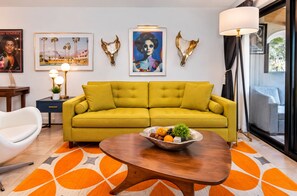 Ein modernes Wohnzimmer mit einem gelben Sofa, einem runden Couchtisch und Wanddekoration, darunter ein Bullkopf und gerahmte Bilder.