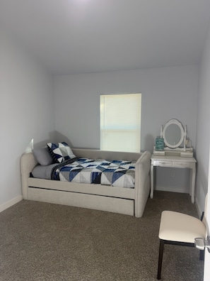 A bedroom with a bed, a bedside table with a mirror, and a chair. - 3BR Family Retreat Mini Golf Soccer Field Fire Pit (Wylie)