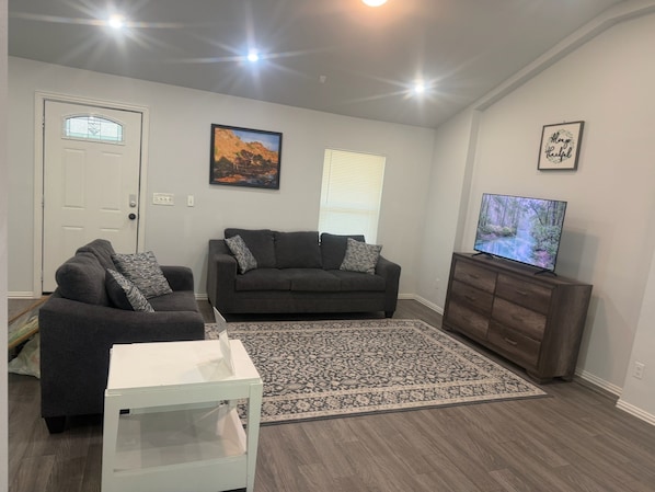 A living room with two sofas, a TV, a rug, and a white cabinet. - 3BR Family Retreat Mini Golf Soccer Field Fire Pit (Wylie)