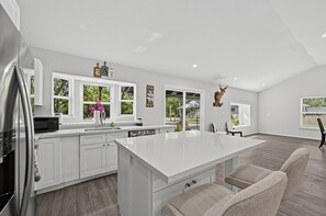 Una cocina moderna con armarios blancos, una isla grande y vistas al exterior.