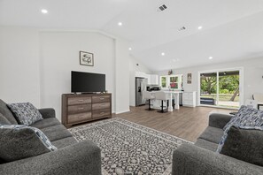 A spacious living area with a flat-screen TV, a wooden cabinet, and a patterned rug.
