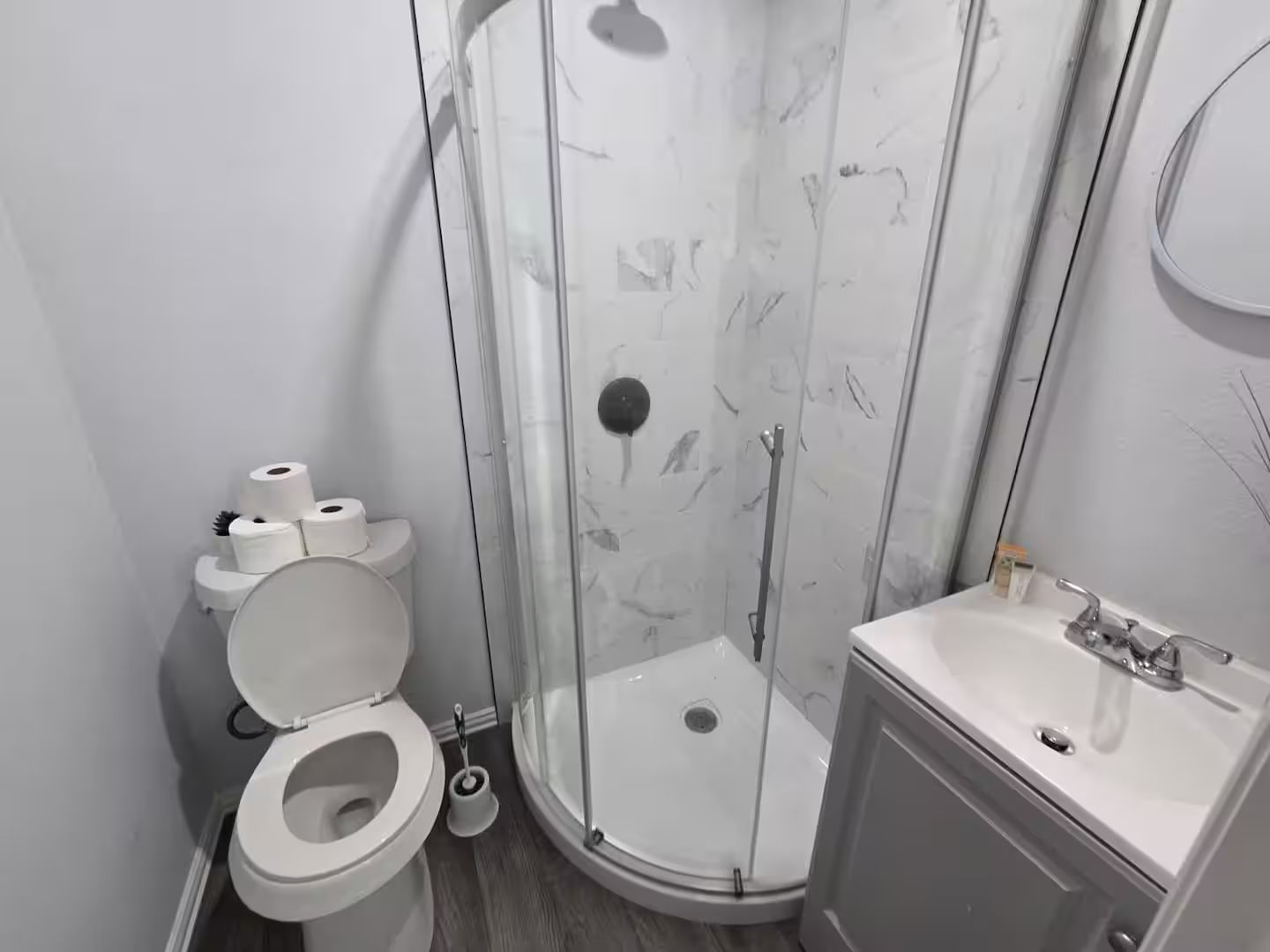 A modern bathroom with a toilet, a shower enclosure, and a sink.