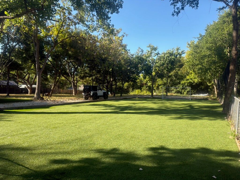 A well-maintained lawn with trees and a parked vehicle.