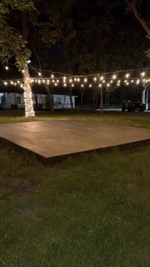 Un espacio al aire libre con una plataforma pavimentada y luces colgantes.