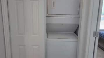 A laundry room with a white door, a Whirlpool washer and dryer, and a 'Laundry' sign above the door.