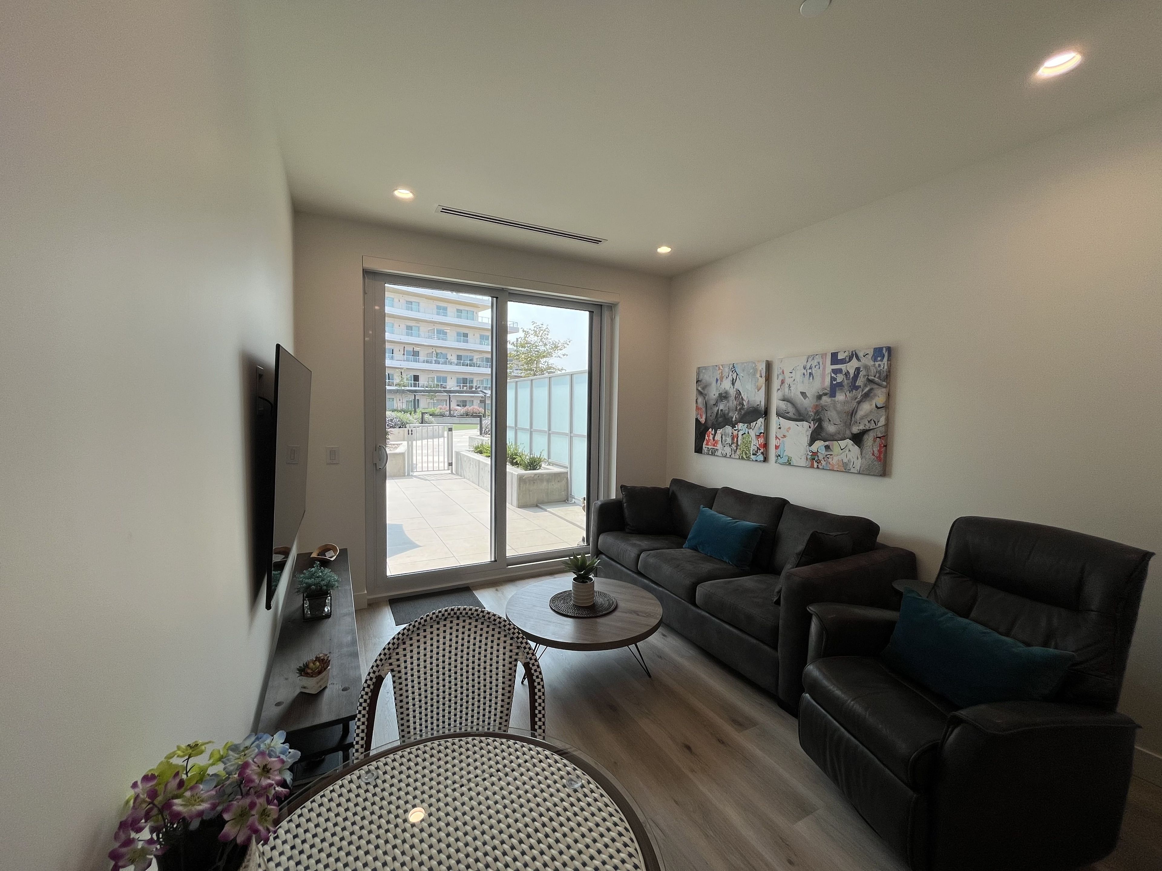 Un salon moderne comprenant un canapé, des fauteuils, une table basse et un téléviseur.