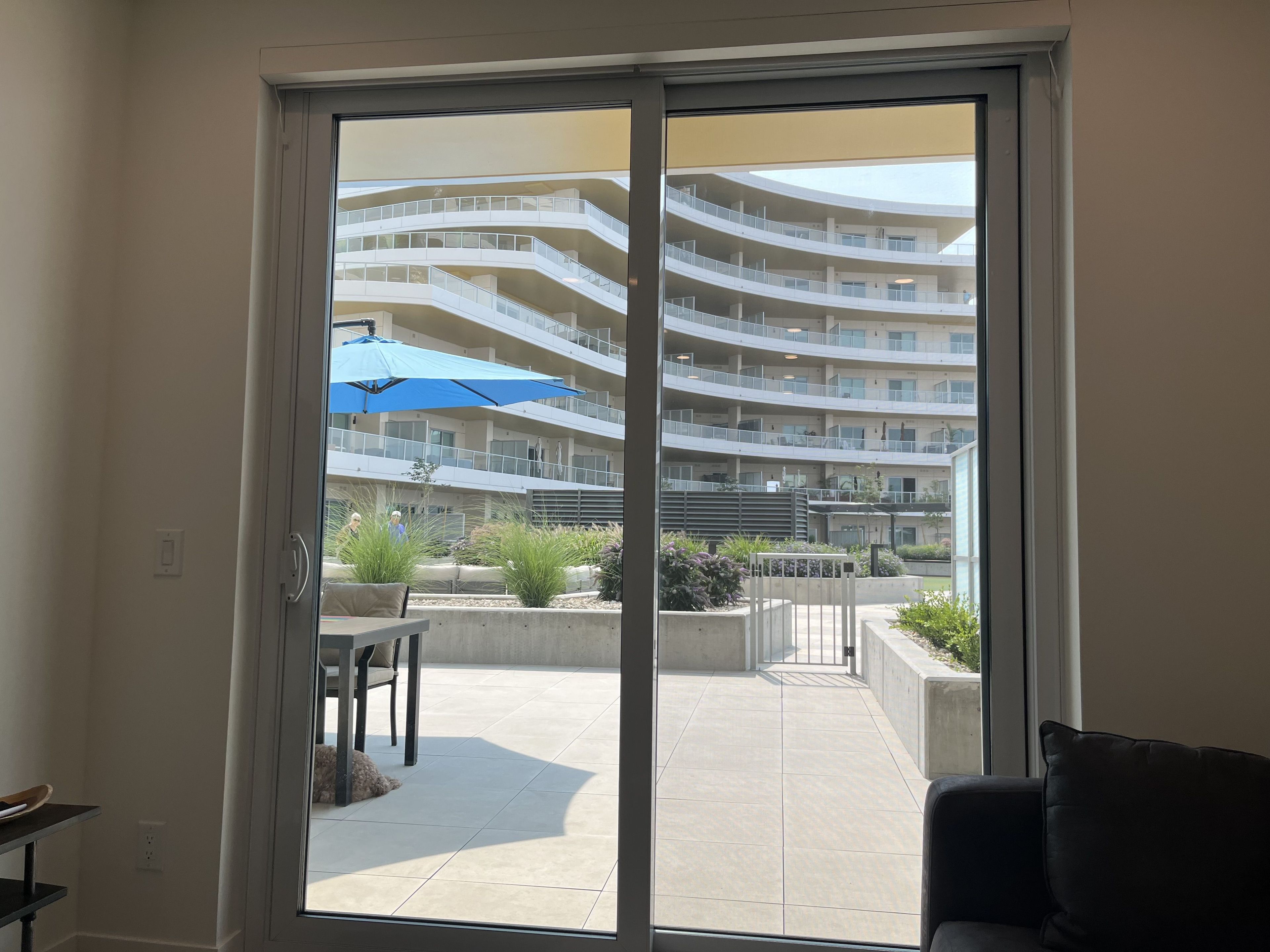 A modern building with multiple balconies and a patio area with outdoor furniture.