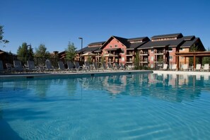 A swimming pool with lounge chairs and a building with multiple balconies. - Steamboat Springs Ski Week-2BR Condo-Sleeps 6,  Jan 3-10, 2027.Champagne Powder. (Steamboat Springs)