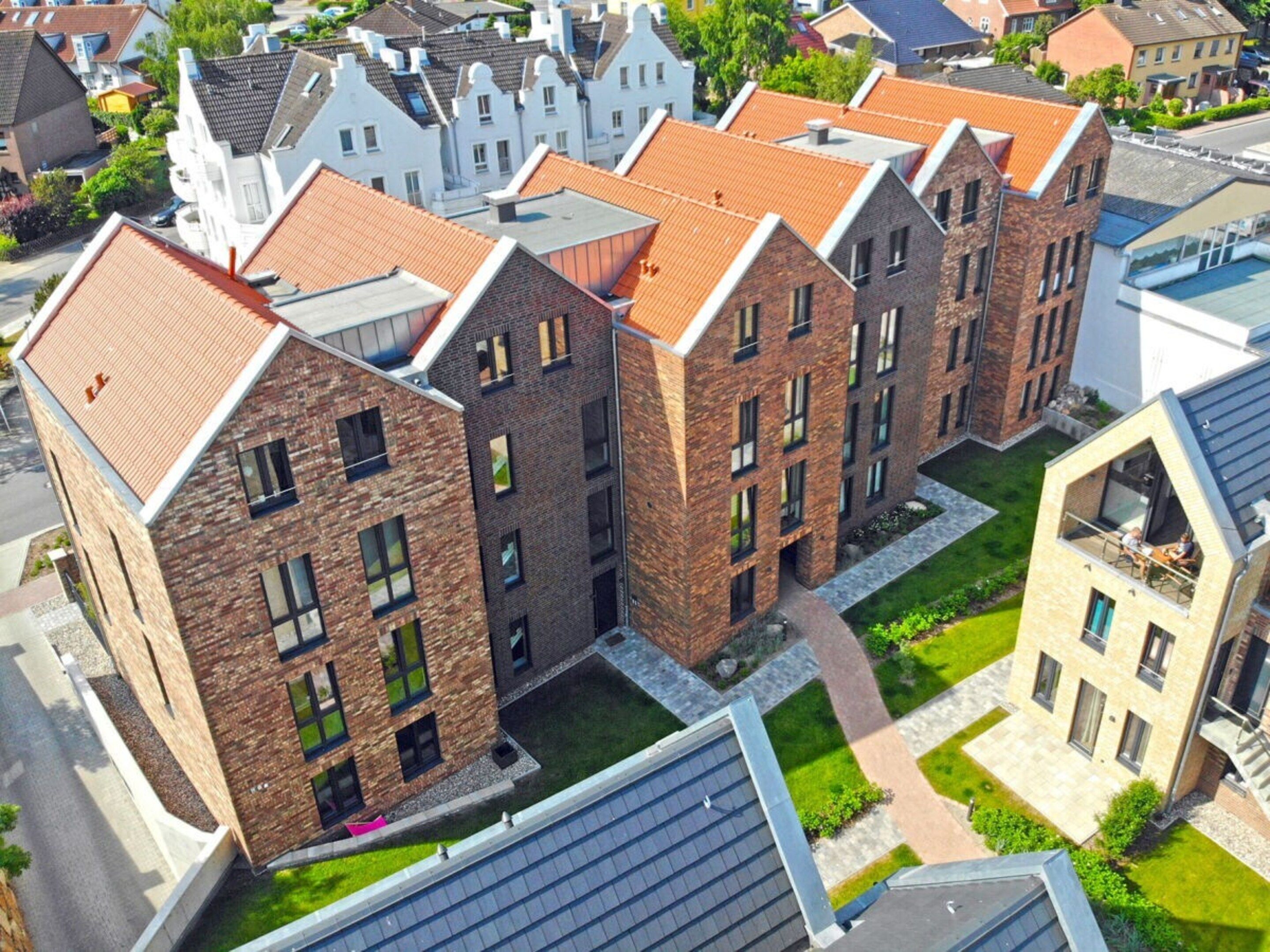 A modern apartment complex with brick facades, multiple balconies, and a central courtyard.