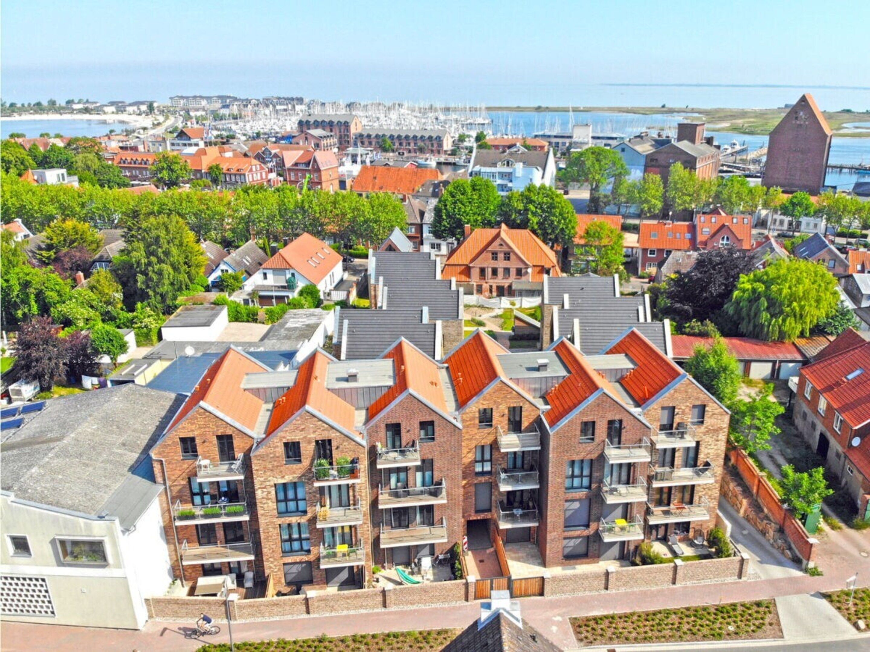 A residential area with modern apartment buildings, a marina in the background, and a clear view of the sea.