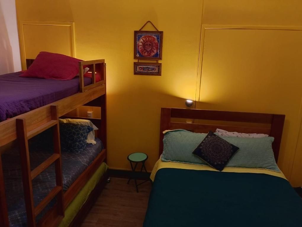 Un dormitorio con literas, una mesa redonda pequeña y un estante fijado a la pared.