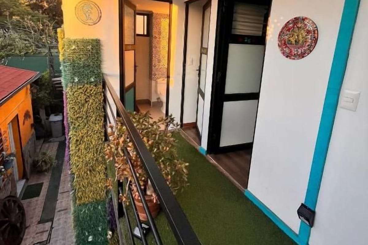 Un corridoio con tappeto verde, una ringhiera e una porta che dà su una stanza.