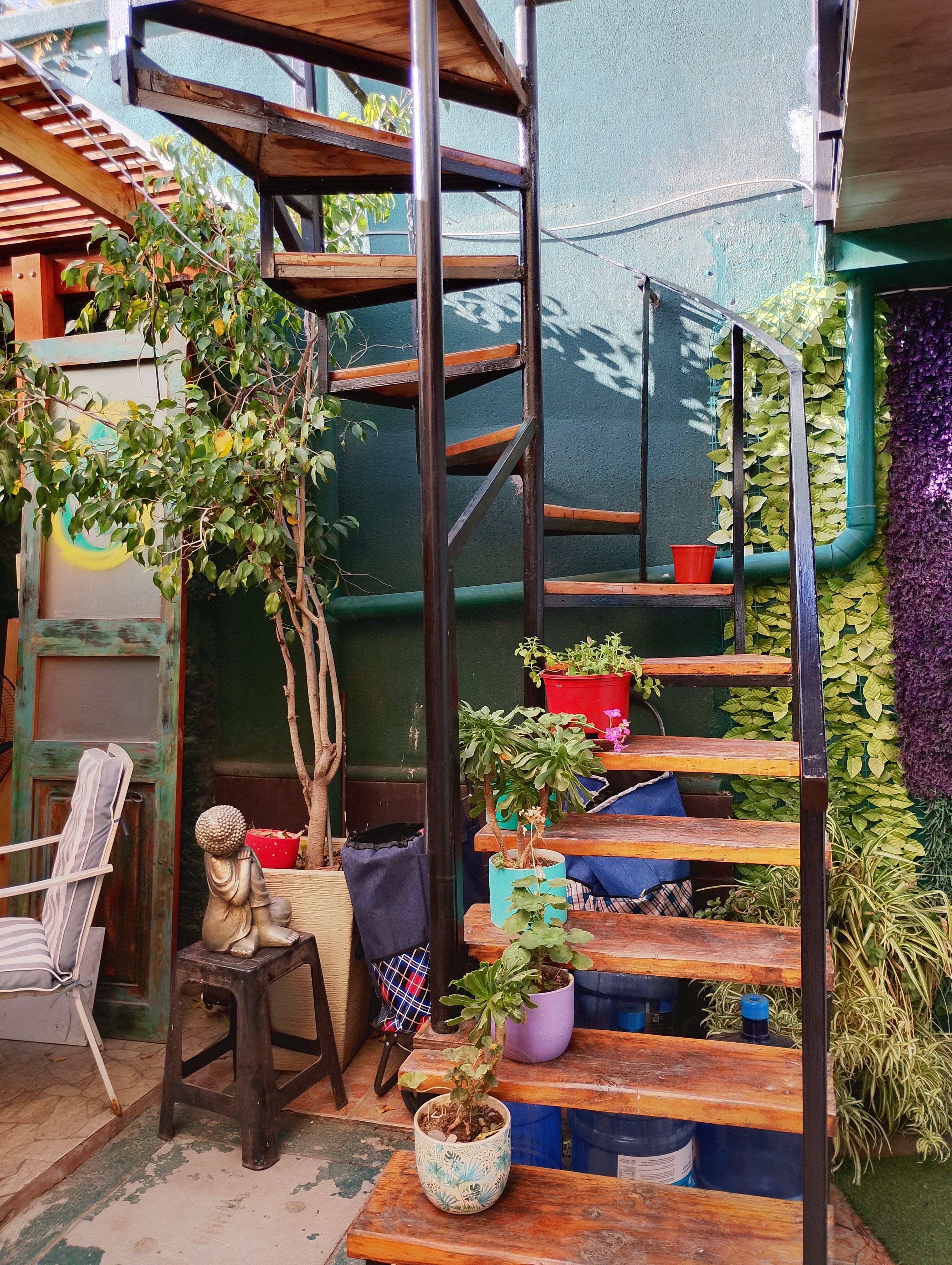 A wooden staircase with potted plants, a statue, and a chair.