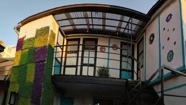 Un edifici amb façana corba, un balcó amb barana metàl·lica i una escala que condueix a un nivell superior.
