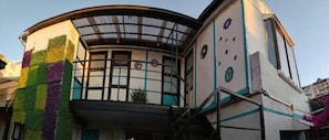 A building with a curved facade, a balcony with a metal railing, and a staircase leading to an upper level. - Hostal La Casa del Puente (Santiago)