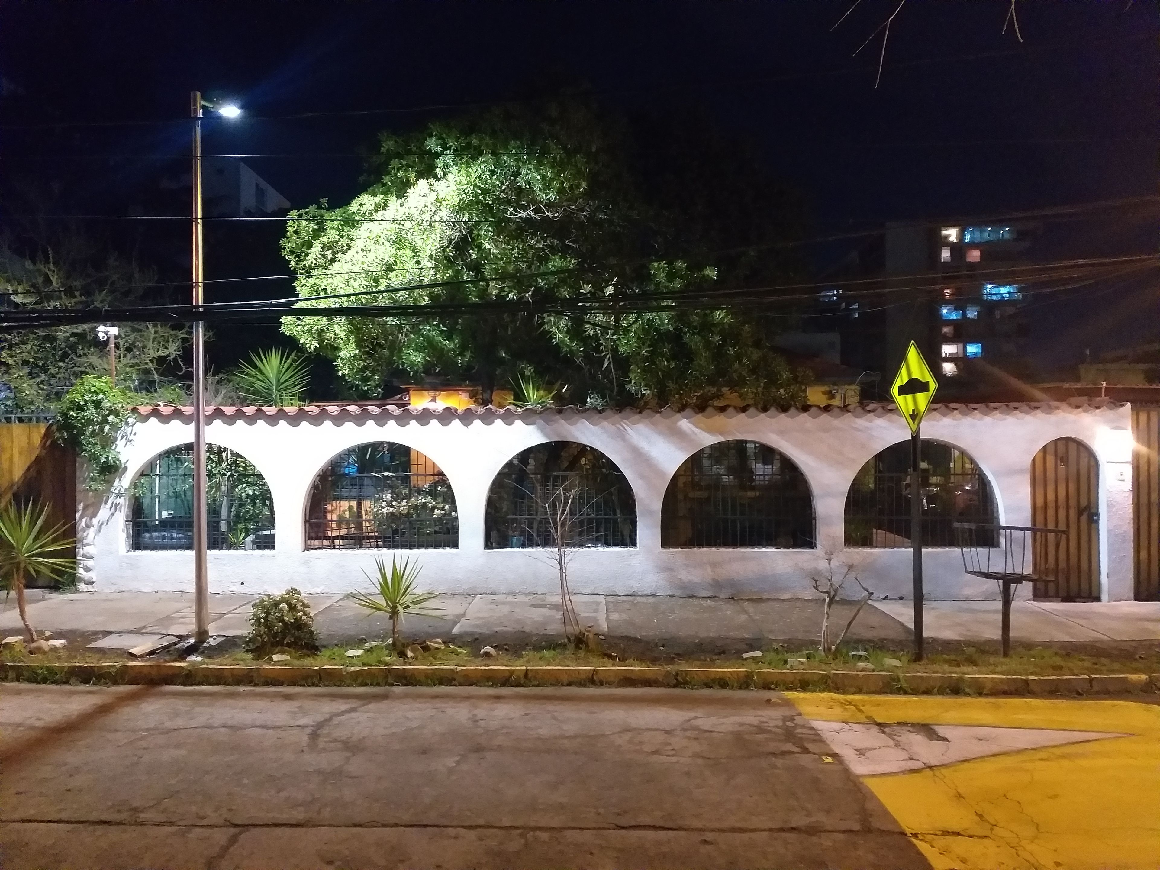 Un edificio con fachada blanca, varios ventanales de arco y una señal de tráfico amarilla.