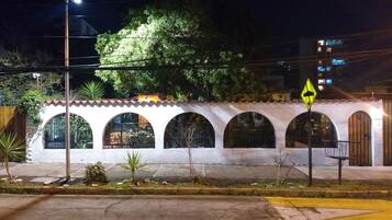 Un edificio con fachada blanca, varios ventanales de arco y una señal de tráfico amarilla.