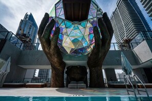 A swimming pool with a unique geometric glass structure above it, surrounded by modern buildings. - Glam Miami Nightlife - Resort Pool - Downtown (Miami)