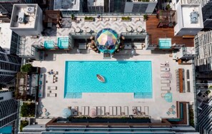 Vista aérea de uma piscina no terraço, com uma escultura esférica central, rodeada por áreas de estar e assentos.