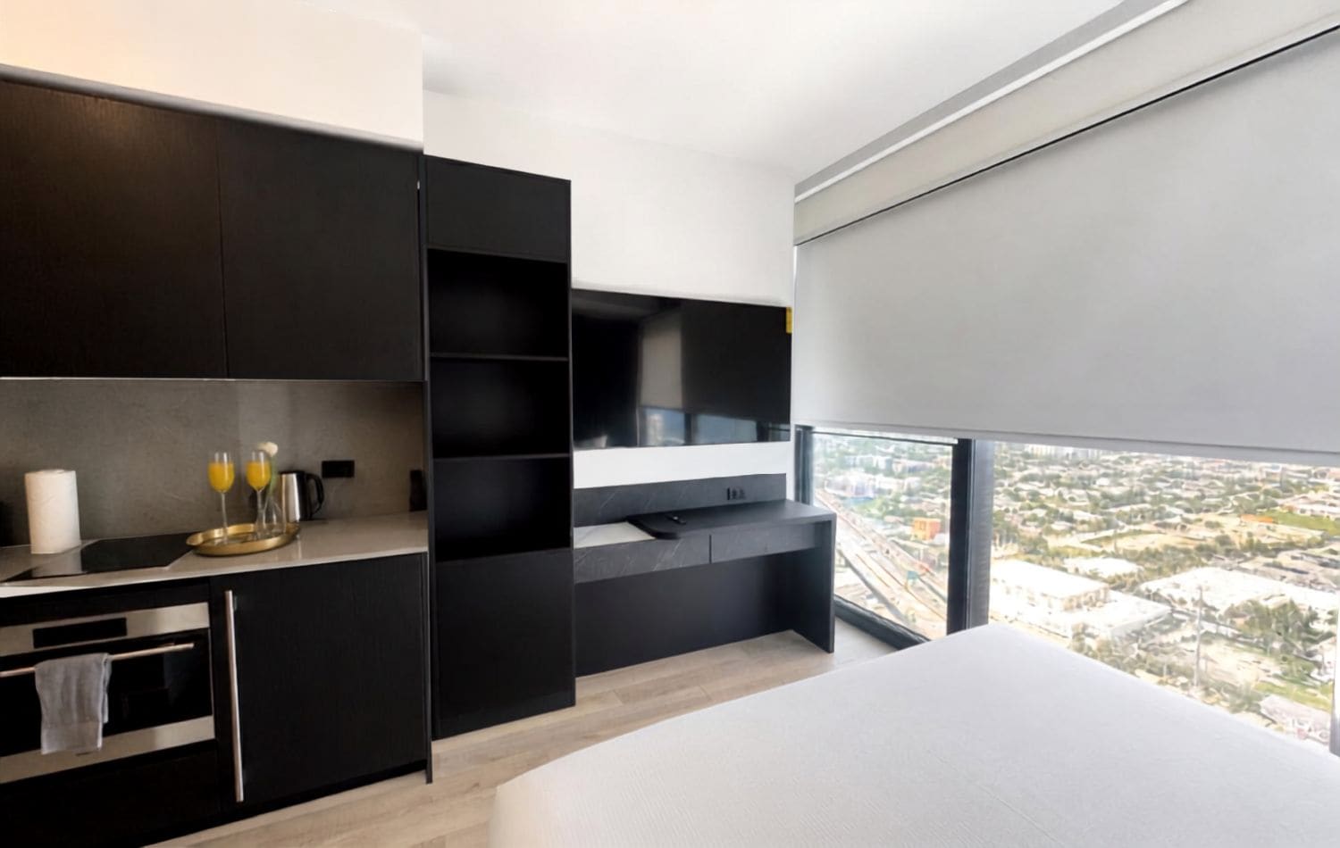 A modern bedroom with a large window, a bed, and a built-in TV.