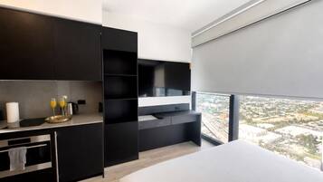 A modern bedroom with a large window, a bed, and a built-in TV.