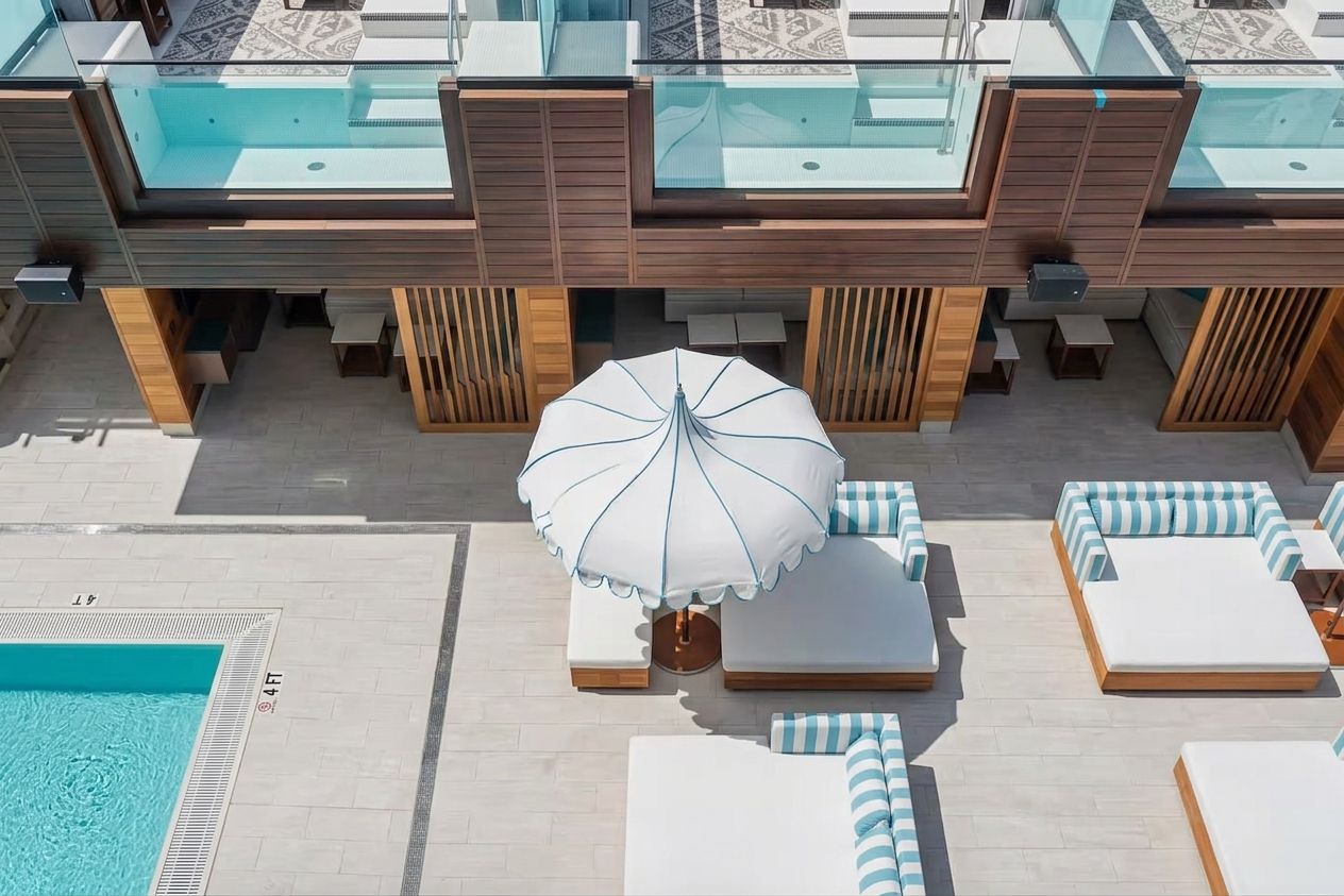 Un espace piscine aménagé sur le toit, avec des chaises longues et un parasol.