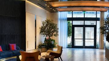 A modern lobby with a curved ceiling, a reception desk, a seating area with chairs and a sofa, and a large window with a view of the outside.