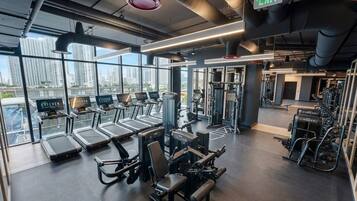 Une salle de sport équipée de tapis de course, d’appareils de musculation et d’autres équipements d’exercice.