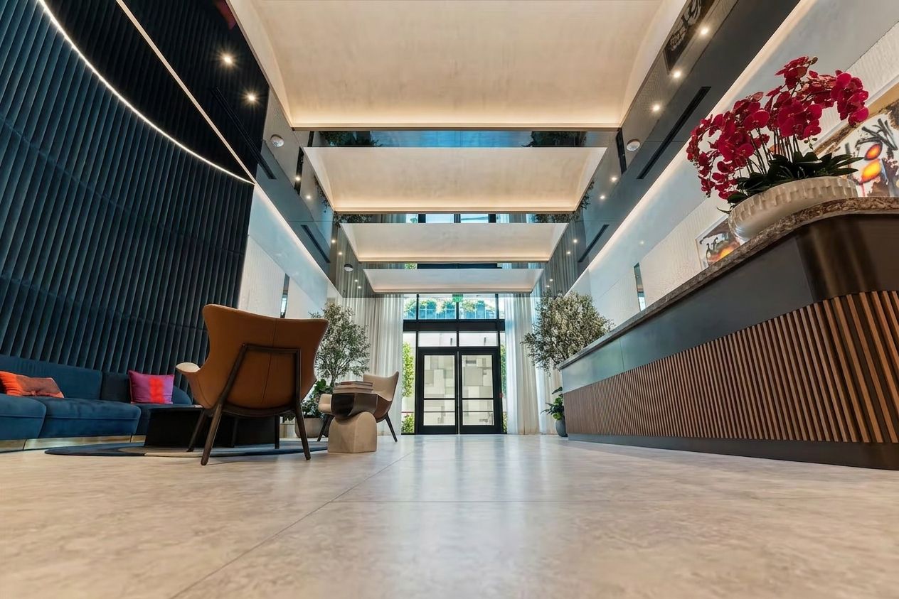 Eine geräumige Lobby mit einer Rezeption, einer Sitzecke und Blick zum Eingang.