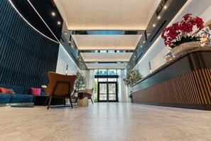 A spacious lobby with a reception desk, seating area, and a view of the entrance. - Glam Miami Nightlife - Resort Pool - Downtown (Miami)