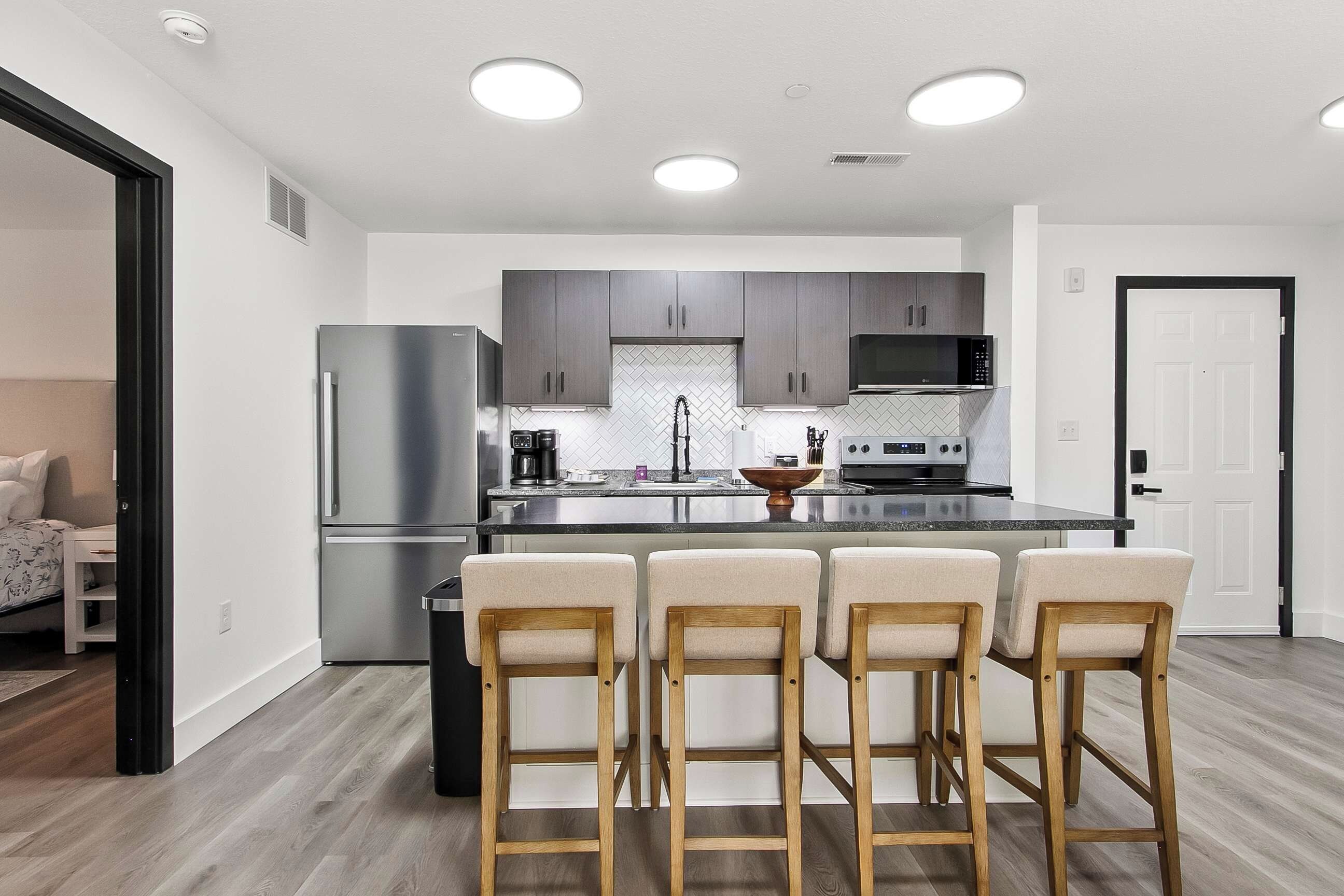 Una cocina moderna con una isla central, electrodomésticos de acero inoxidable y un respuesto de azulejos en patrón de espiga.