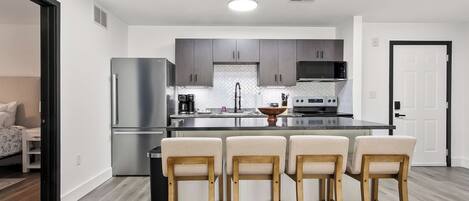 Una cocina moderna con una isla central, electrodomésticos de acero inoxidable y un respuesto de azulejos en patrón de espiga.