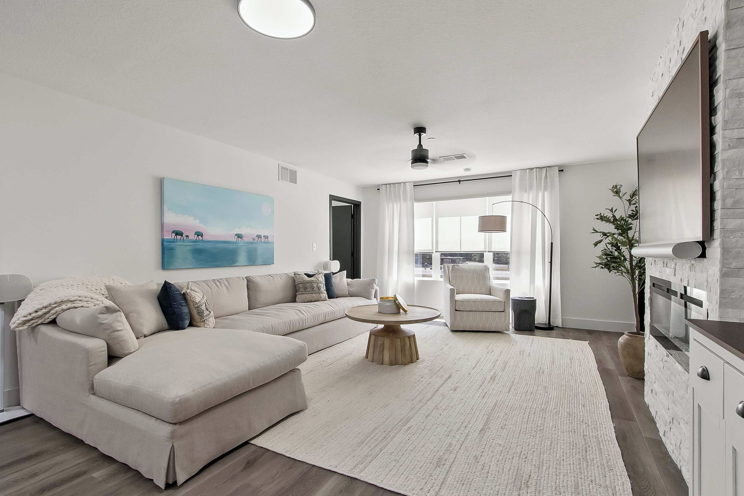 A modern living room with a sectional sofa, a round coffee table, and a painting on the wall.